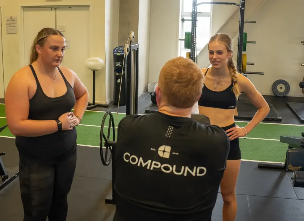 Compound Gym members and a trainer working on the gym floor in Dunedin