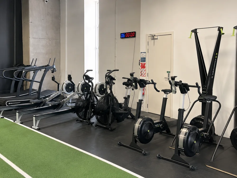 Free-form runners, Concept2 rowers, assault bikes and Concept2 ski ergs beside the turf lane at Compound Gym