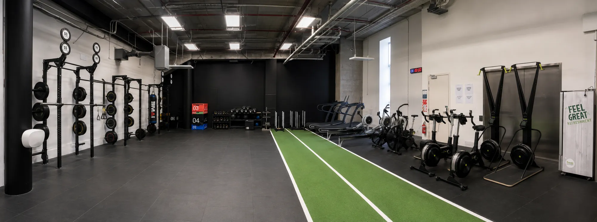 The conditioning end of Compound Gym: the 46m turf lane running the length of the room, with the rig, plyo boxes, medicine balls and sleds on one side and treadmills, free-form runners, rowers, assault bikes and ski ergs on the other