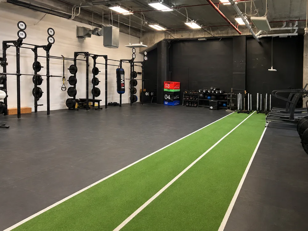 The 46m indoor turf lane at Compound Gym, with the rig, plyo boxes, medicine balls and sleds alongside